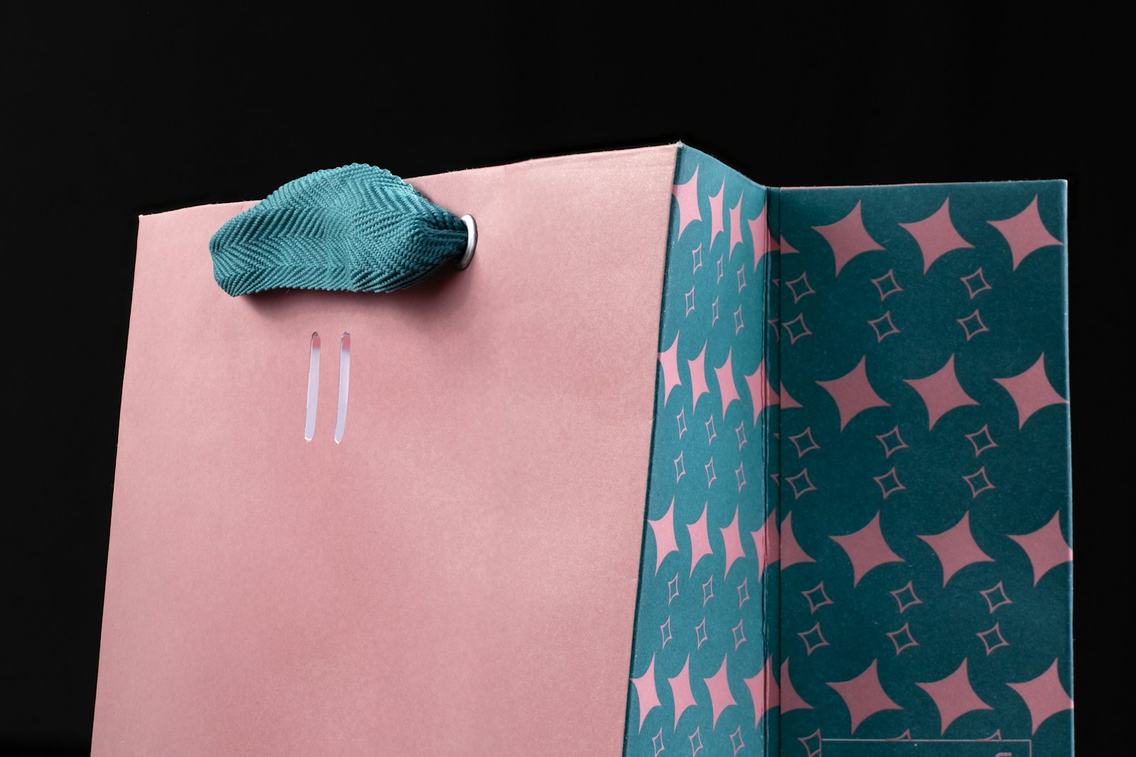 a pink and blue paper bag with a bow on it